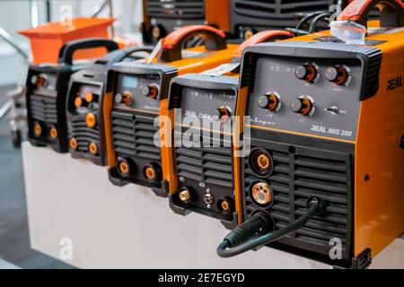 Row of protective welding mask helmets on table at exhibition, trade show Stock Photo