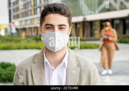 Portrait of young businessman in protective mask looking at camera while standing in the city Stock Photo
