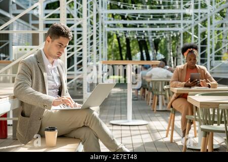 Group of people using their gadgets and working online while sitting in cafe Stock Photo