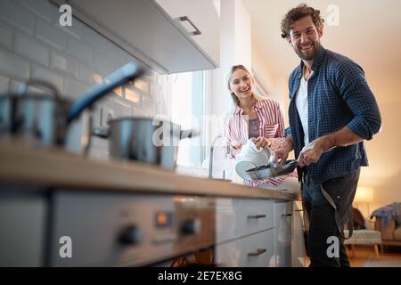 Young couple doing housework and posing for a photo in a relaxed atmosphere in the kitchen. Kitchen, housework, home, relationship Stock Photo