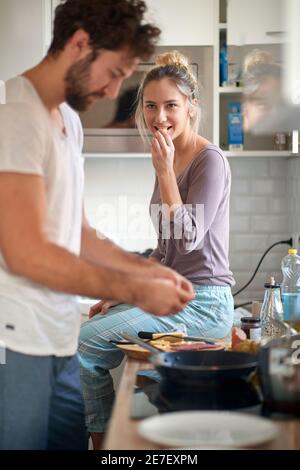 A young man in the kitchen preparing a meal for his girlfriend. Cooking, home, kitchen, relationship Stock Photo
