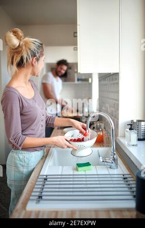 A young couple enjoying preparing a meal in a relaxed atmosphere together. Kitchen, home, cooking, relationship Stock Photo