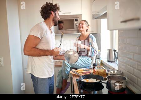 A young couple in love having fun while preparing a breakfast together on a beautiful morning. Cooking, together, kitchen, relationship Stock Photo