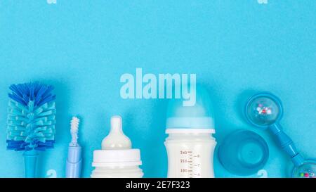 Baby food background with bottles with milk and bottle brush accessories on blue table top view frame copy space Stock Photo