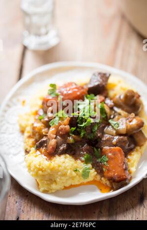 Boeuf bourguignon with carrots, mushrooms, topped with parsley served with polenta Stock Photo