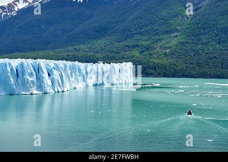 Blue ice of Perito Moreno Glacier in Glaciers national park in Patagonia, Argentina with a tourist boat on the turquoise water of Lago Argentino in th Stock Photo