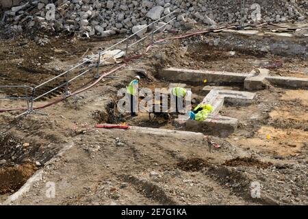Archaeologists digging, excavating & working at archaeological dig on demolition site (historic remains of walls) - Hudson House, York, England, UK. Stock Photo