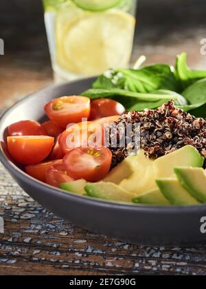 Close-up on a bowl of sliced tomato, avocado, basil and quinoa Stock Photo