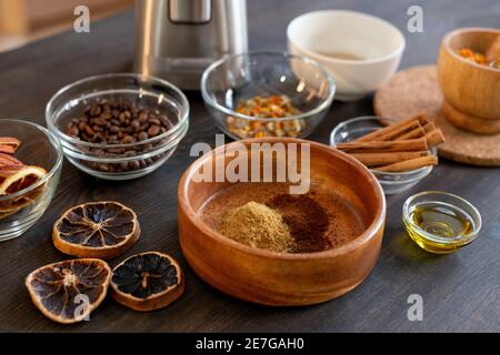 Group of bowls with coffee beans, dry flowers and orange slices, cinnamon sticks, ground candied fruits and other ingredients for making soap Stock Photo