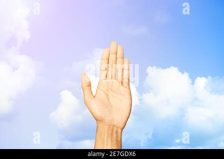 Young man hand showing refusal gesture behind of  blue sky and clouds background with copy space for wallpaper or banner Stock Photo
