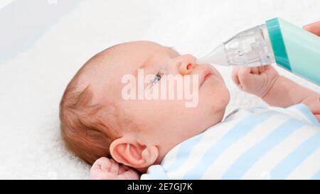 Closeup of mother using electric nasal aspirator to remove mucus from her newborn baby nose. Concept of babies and newborn hygiene and healthcare Stock Photo