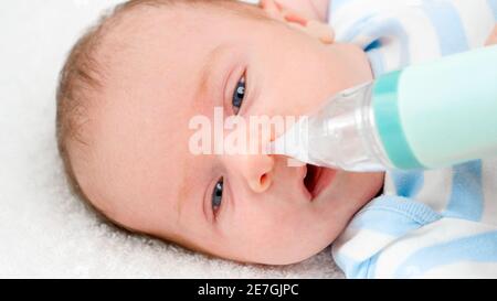 Closeup slow motion of cleaning tiny nose of newborn baby with electric aspirator. Concept of babies and newborn hygiene and healthcare. Caring Stock Photo