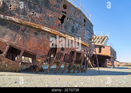 San Gregorio, Argentina-27.11.2018 old rusty and rotten ship wreck with holes in carcass, lying behind long gras on the beach of the coast line of the Stock Photo