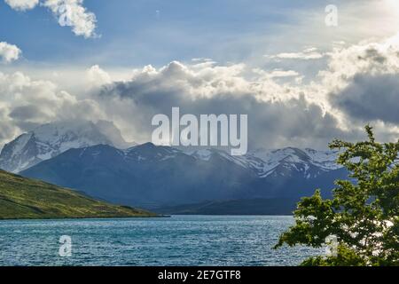 Towers of torres del Paine national park covered in clouds with dark green forest a lake and snow covered mountains of the Andes in Patagonia southern Stock Photo