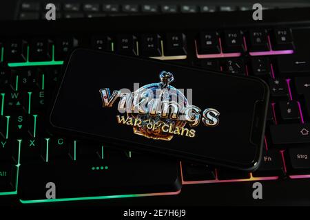 Viersen, Germany - January 9. 2021: Closeup of smartphone screen with logo lettering of online game vikings war of clans on illuminated computer keybo Stock Photo