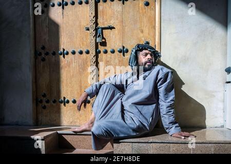 Saudi Arabian men sitting in front of the closed shop in Al Hasa, Saudi Arabia. Stock Photo