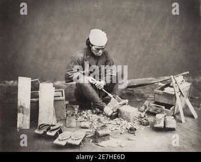 Vintage 19th century photograph: Carpenter, shoe maker at work, making wooden shoes, Japan Stock Photo