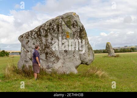 With a man standing for scale, the Longstones, two standing stones, also known as 'Adam' (nearest) and 'Eve', Beckhampton, Wiltshire, England. Stock Photo