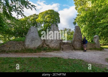 Man standing in front of the entrance stones to Wayland’s Smithy a Neolithic tomb on the Downs above the Vale of the White Horse, Oxfordshire, UK. Stock Photo
