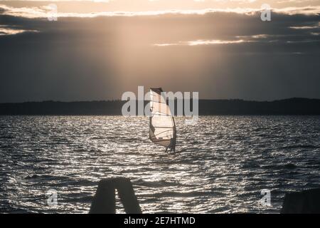 Windsurfer Surfing The Wind On Waves In Neusiedl Lake in Austria at Sunset. Recreational Water Sport. Summer Fun Adventure Activity. Stock Photo