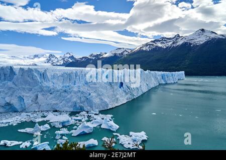 Blue ice of Perito Moreno Glacier in Glaciers national park in Patagonia, Argentina with the turquoise water of Lago Argentino in the foreground, dark Stock Photo