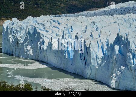 Blue ice of Perito Moreno Glacier in Glaciers national park in Patagonia, Argentina with the turquoise water of Lago Argentino in the foreground, dark Stock Photo
