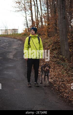 young man in a yellow jacket aged 20-24 on a walk with a Czech mustache, a hunting dog. Binary portrait of taking care of pet, love and relationship. Stock Photo