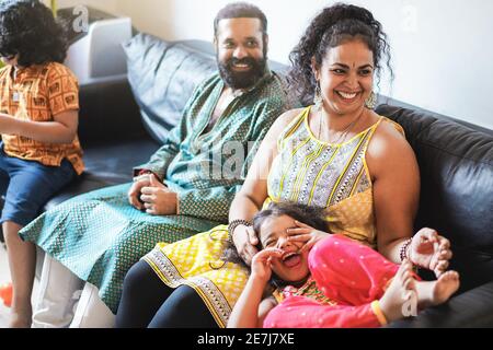 Happy indian family having fun at home sitting on sofa - Focus on mother Stock Photo