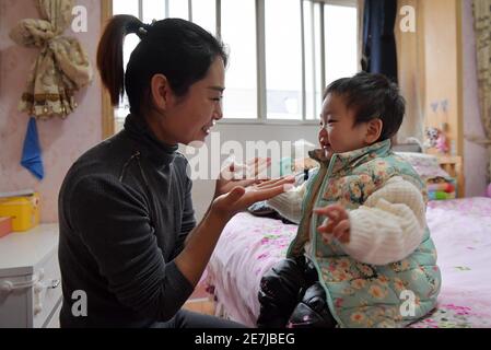 (210130) -- NANCHANG, Jan. 30, 2021 (Xinhua) -- Wang Ajing, an attendant of the China Railway Nanchang Bureau Group Co., Ltd., plays with her second child at her home in Jiujiang City of east China's Jiangxi Province, Jan. 25, 2021. 30-year-old Wang Ajing, who is from Xianyang City of northwest China's Shaanxi Province, is now serving as an attendant of the China Railway Nanchang Bureau Group Co., Ltd. Before she left her hometown in 2008, Wang's parents gave her a family photo, which she carried with her ever since then.  Wang's mother, for some reason, was not able to attend her wedding when Stock Photo
