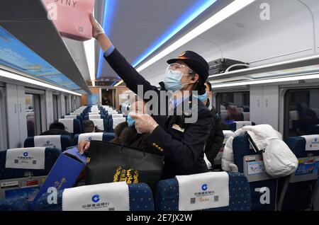 (210130) -- NANCHANG, Jan. 30, 2021 (Xinhua) -- Wang Ajing, an attendant of the China Railway Nanchang Bureau Group Co., Ltd., helps a passenger to place her luggage aboard a train on Jan. 26, 2021. 30-year-old Wang Ajing, who is from Xianyang City of northwest China's Shaanxi Province, is now serving as an attendant of the China Railway Nanchang Bureau Group Co., Ltd. Before she left her hometown in 2008, Wang's parents gave her a family photo, which she carried with her ever since then.  Wang's mother, for some reason, was not able to attend her wedding when she got married in Jiangxi in 201 Stock Photo
