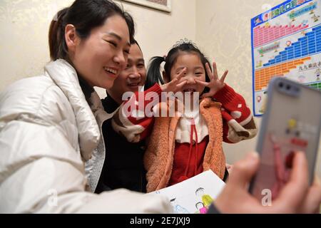 (210130) -- NANCHANG, Jan. 30, 2021 (Xinhua) -- Wang Ajing, an attendant of the China Railway Nanchang Bureau Group Co., Ltd., together with her husband and daughter, chats with her parents via video link at her home in Jiujiang City of east China's Jiangxi Province, Jan. 25, 2021. 30-year-old Wang Ajing, who is from Xianyang City of northwest China's Shaanxi Province, is now serving as an attendant of the China Railway Nanchang Bureau Group Co., Ltd. Before she left her hometown in 2008, Wang's parents gave her a family photo, which she carried with her ever since then. Wang's mother, for so Stock Photo