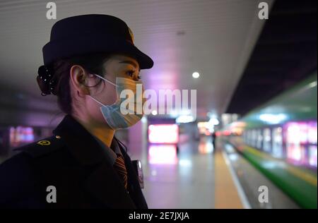(210130) -- NANCHANG, Jan. 30, 2021 (Xinhua) -- Wang Ajing, an attendant of the China Railway Nanchang Bureau Group Co., Ltd., waits for her train to arrive at a railway station in Nanchang City, capital of east China's Jiangxi Province, Jan. 26, 2021. 30-year-old Wang Ajing, who is from Xianyang City of northwest China's Shaanxi Province, is now serving as an attendant of the China Railway Nanchang Bureau Group Co., Ltd. Before she left her hometown in 2008, Wang's parents gave her a family photo, which she carried with her ever since then.  Wang's mother, for some reason, was not able to att Stock Photo