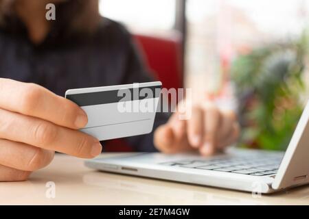 Close up hands with a plastic card. Entering card number on laptop keyboard. Online pay concept. Stock Photo