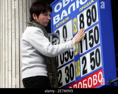 A woman changes the rates of a currency exchange rate board in Kiev February 26, 2009. Ukraine has been hit hard by the global financial crisis and is expected to fall deep into recession this year as the currency weakens and industry has all but ground ot a halt.   REUTERS/Konstantin Chernichkin (UKRAINE)