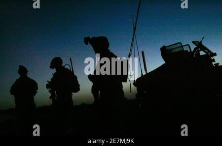 U.S. Army soldiers stand near their vehicle before dawn as they prepare to take part in a joint operation with Iraqi soldiers near Mahmudiya, south of Baghdad April 16, 2007.  REUTERS/Bob Strong (IRAQ)