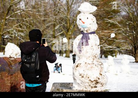 Berlin, Germany. 30th Jan, 2021. Germany, Berlin, January 30, 2021: A man photographs a snowman wearing a face mask at Berlins Tiergarten. Berlin residents are urgently required to reduce physical social contact with people from outside the home to the absolute minimum. People may only leave their home for important reasons. (Photo by Jan Scheunert/Sipa USA) Credit: Sipa USA/Ģ����ý Live News Stock Photo