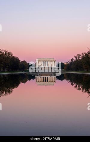 A pink sky and the ivory marble iconic Lincoln Memorial is mirrored in the Reflecting Pool on a crisp Autumn morning in Washington, DC. Located at the Stock Photo