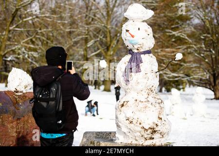 Berlin, Berlin, Germany. 30th Jan, 2021. A man photographs a snowman wearing a face mask at Berlins Tiergarten. Berlin residents are urgently required to reduce physical social contact with people from outside the home to the absolute minimum. People may only leave their home for important reasons. Credit: Jan Scheunert/ZUMA Wire/Ģ����ý Live News Stock Photo