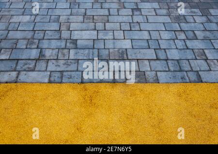 Playground with yellow rubber surface coating and gray tiles, trend colors 2021 Stock Photo