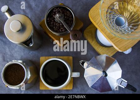 Top view of coffee makers, grinder, and a cup of coffee on a gray background Stock Photo
