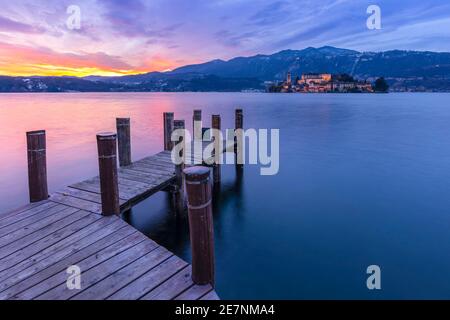 Sunset near a pier in front of San Giulio island and Lake Orta. Orta San Giulio, Orta Lake, Province of Novara, Piedmont, Italy. Stock Photo