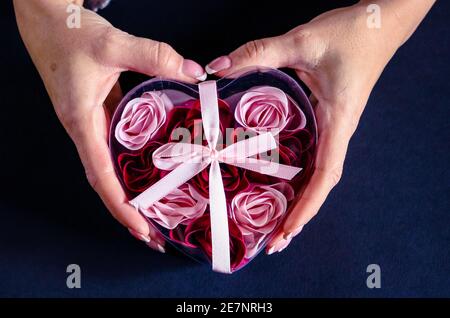 Hands holding heart shaped box with roses Stock Photo