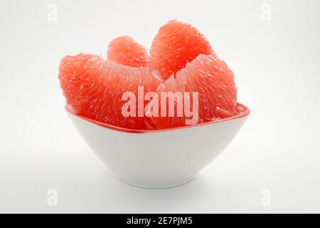juicy red grapefruit slices in a bowl on a white background Stock Photo