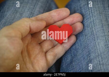 Man holding a red origami heart in his palm. Close up. Stock Photo