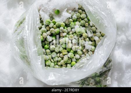 Green frozen peas covered with tiny ice crystals in a plastic bag. top view. Stock Photo
