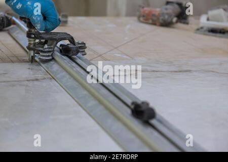 Man working at the cut ceramic tile on the manual tile cutting Stock Photo