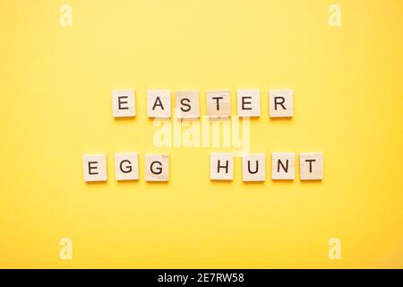 Phrase easter egg hunt made from wooden blocks on a light yellow background Stock Photo