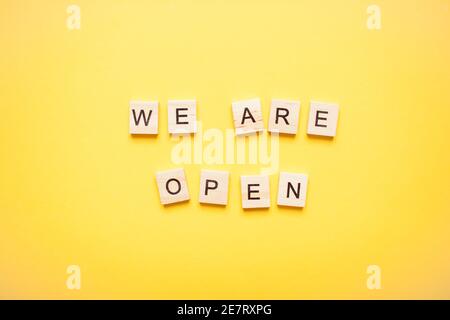 Phrase we are open made from wooden blocks on a light yellow background Stock Photo