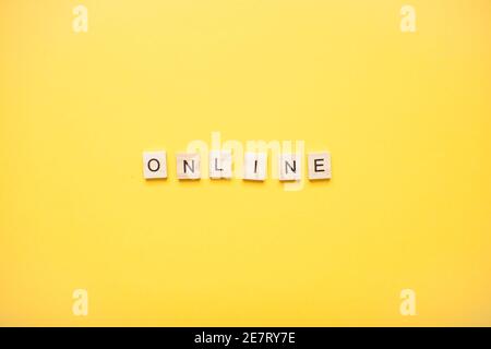 Phrase online made from wooden blocks on a light yellow background Stock Photo