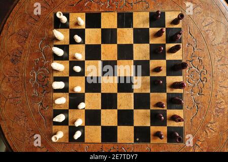 The top view of an old chess set on a purpose build carved chess board and table in an English country house Stock Photo